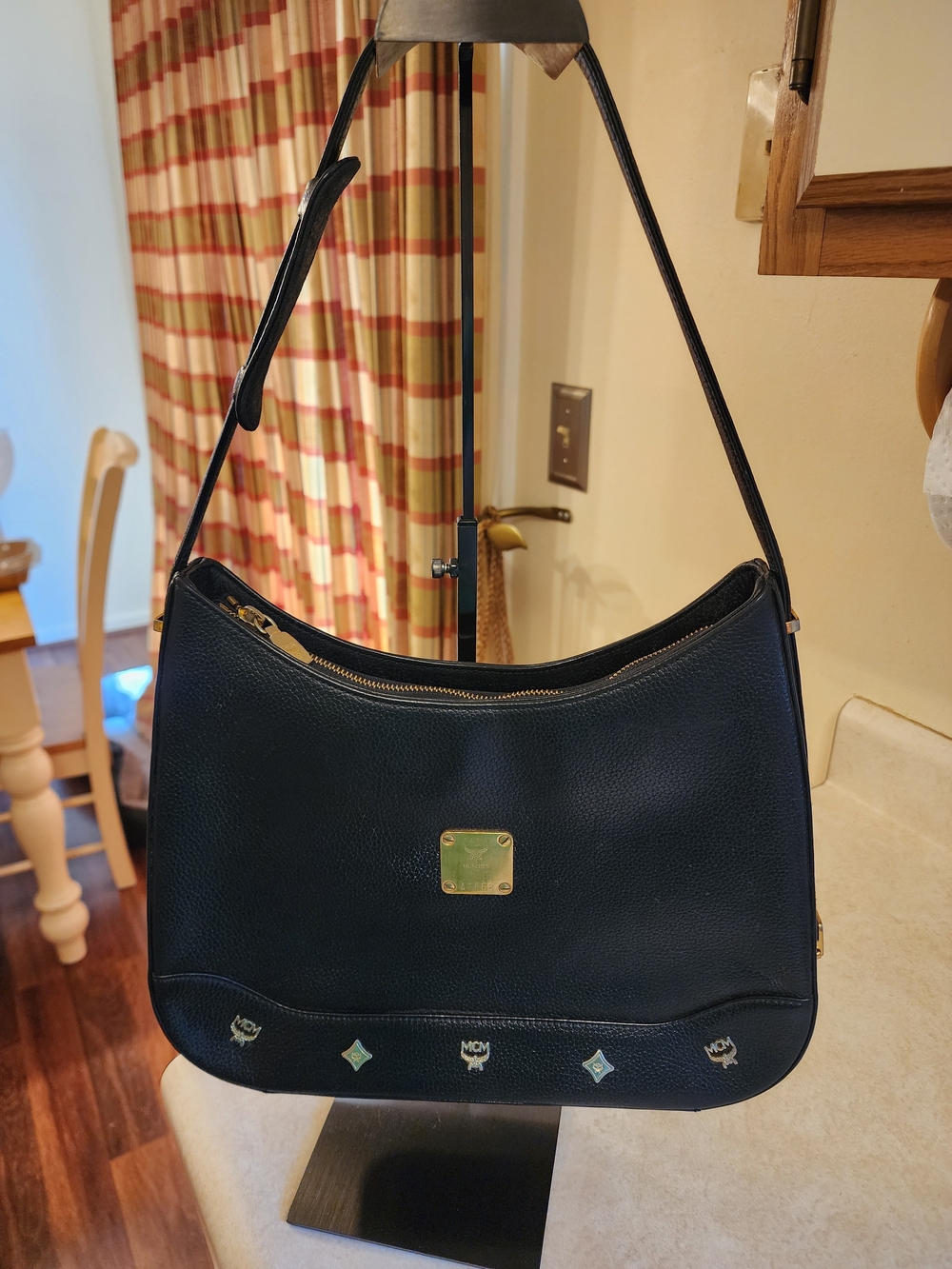 black MCM leather shoulder hobo features a distinctive gold-toned logo plaque